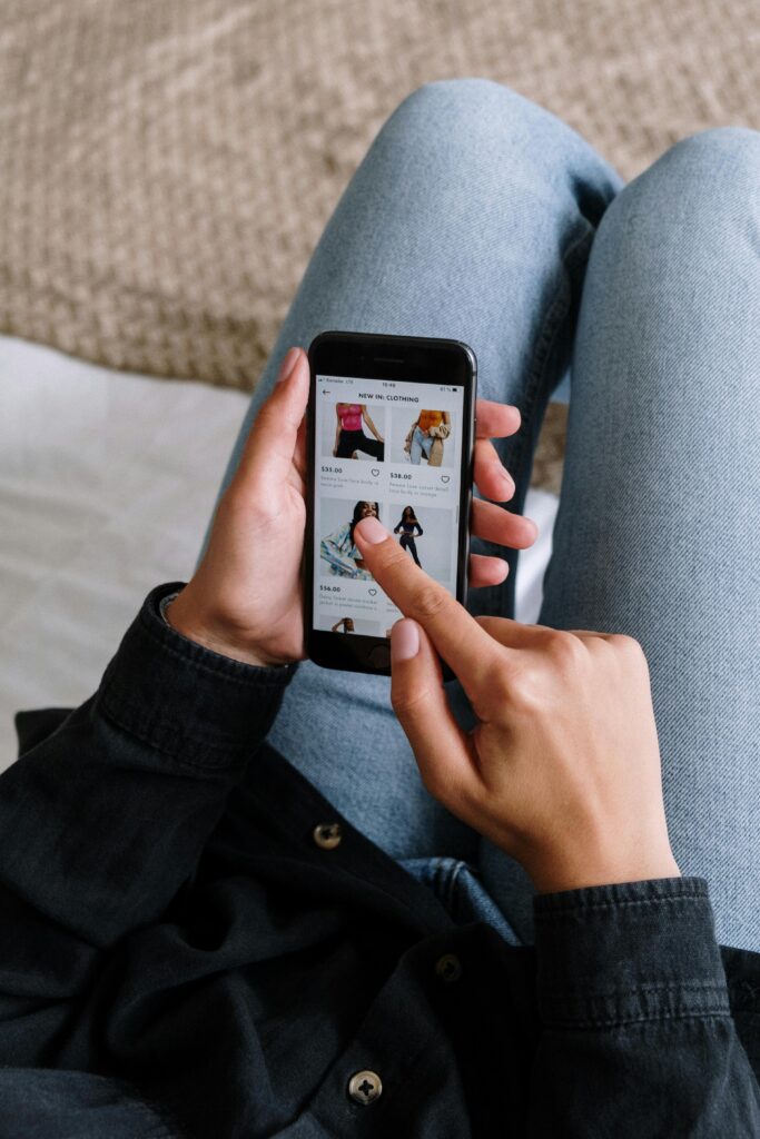 pexels-photo-5076516-5076516 Close-up of a woman shopping online on a smartphone while relaxing at home.